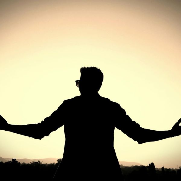 Man meditating peacefully outdoors with a natural background.