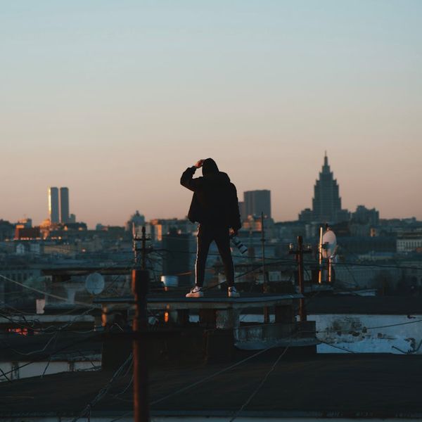 Silhouette of a man stretching with a city skyline at dawn.